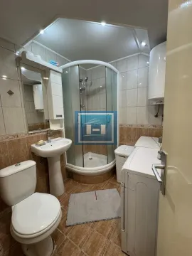 Bathroom equipped with a shower cabin, washbasin, toilet, and washing machine. - image 4