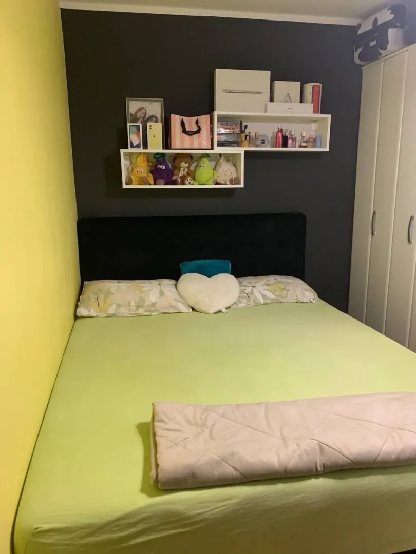 Spavaća soba sa bračnim krevetom, policama i bijelim ormarom.