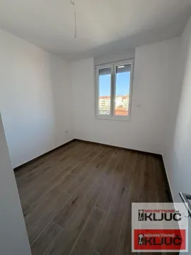 Prazna neopremljena soba sa prozorom i podom od keramičkih pločica u imitaciji drveta. - image 4