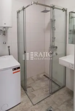 Modern bathroom with a walk-in shower, washbasin, and washing machine. - image 13