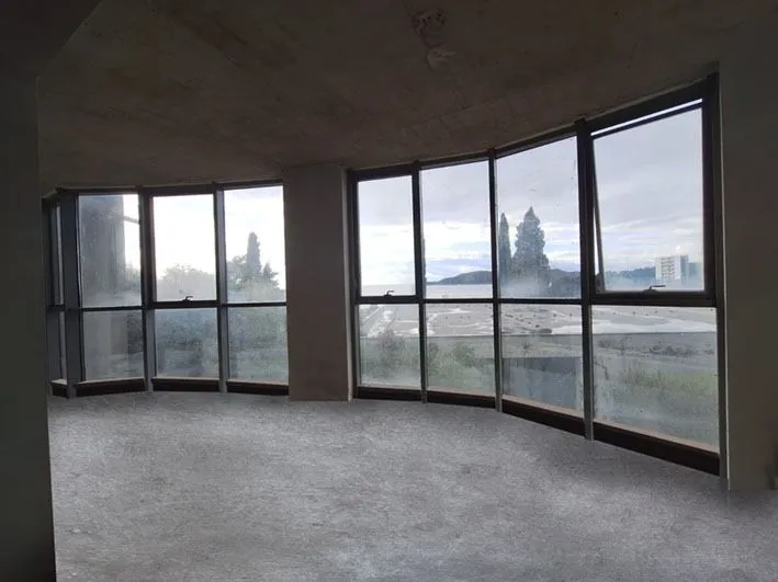 Unfinished room under construction with large windows and a sea view.
