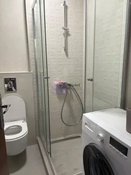 Bathroom equipped with a shower cabin, toilet, and washing machine. - image 4