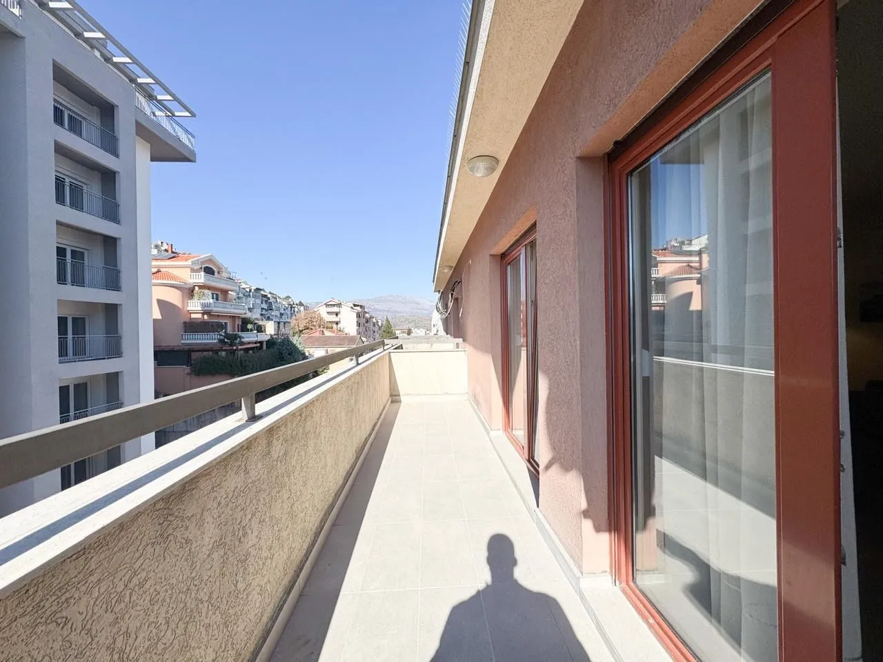 Prostrani balkon sa pogledom na okolne zgrade i grad.