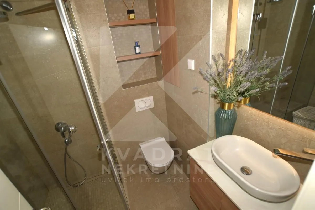 Modern bathroom with a walk-in shower, washbasin, and wall-mounted toilet.