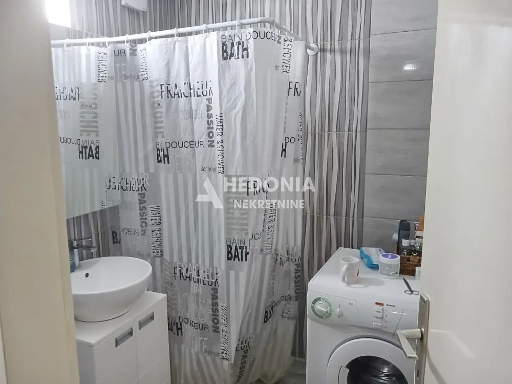 Kupatilo sa umivaonikom, tuš kabinom sa zavesom i veš mašinom.