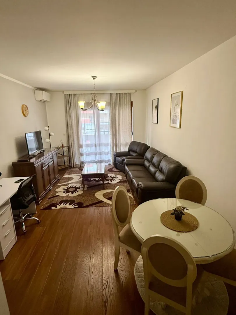 A bright living room featuring a leather sofa set and a dining table.