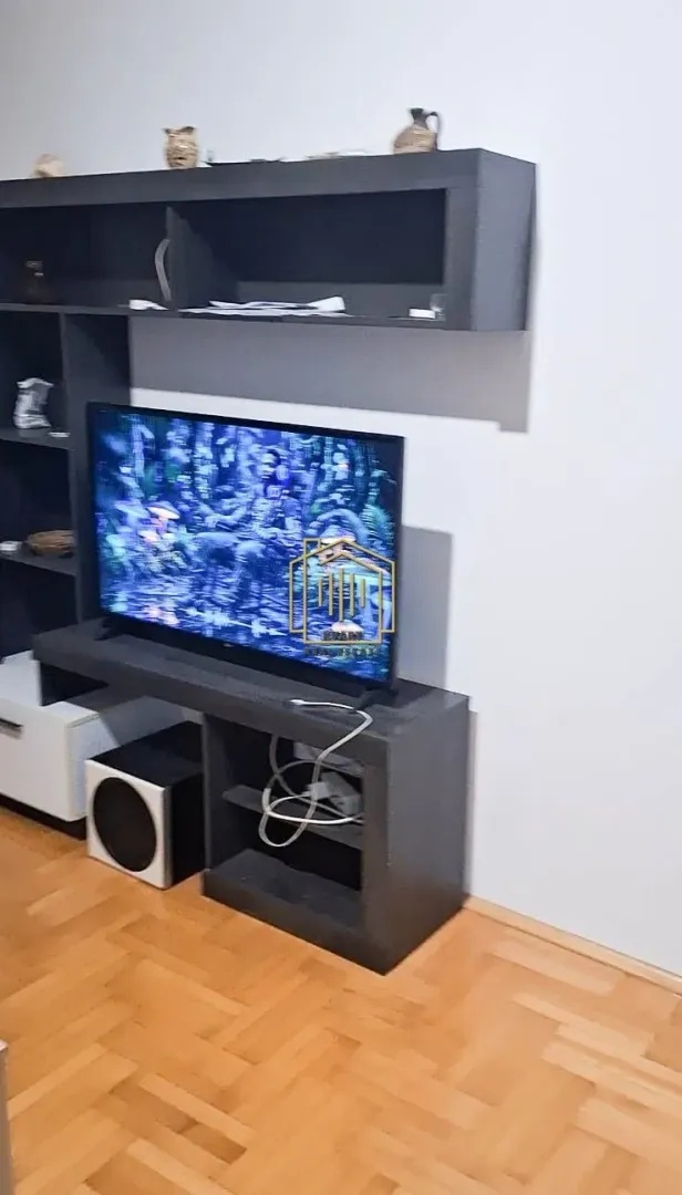 Dnevna soba sa televizorom i zidnim policama.