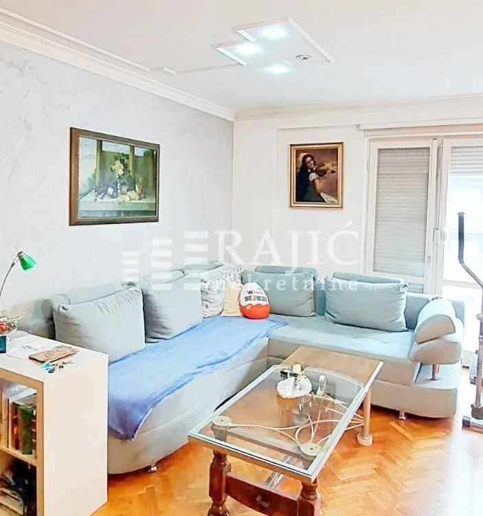 Living room with a sectional sofa, coffee table, and paintings on the wall.