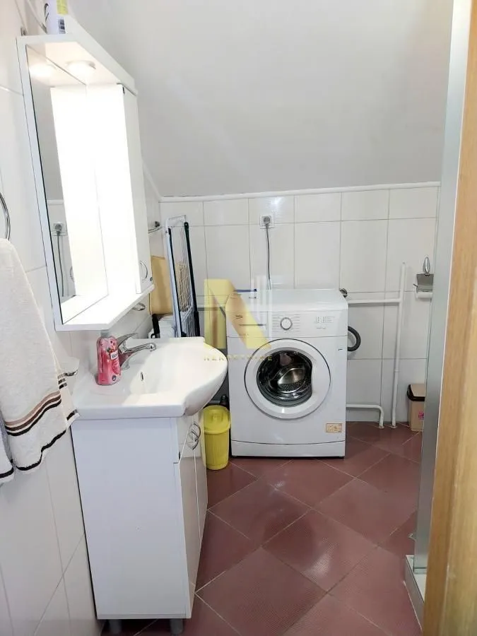 Kupatilo sa umivaonikom, ormarićem, ogledalom i veš mašinom.