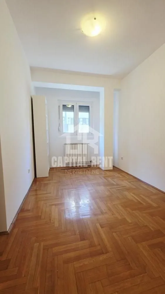 Empty room with parquet flooring and a window.