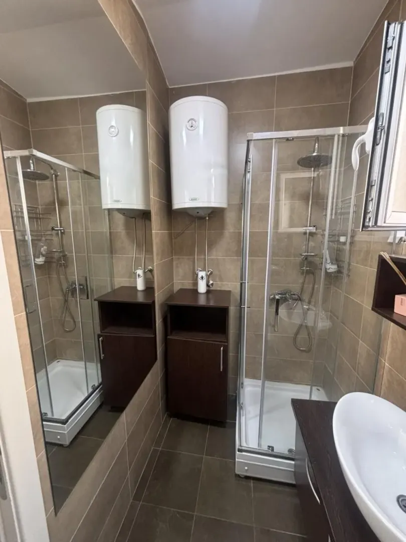 Bathroom with a shower cabin, washbasin, and water heater.