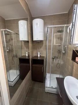 Bathroom with a shower cabin, washbasin, and water heater. - image 7