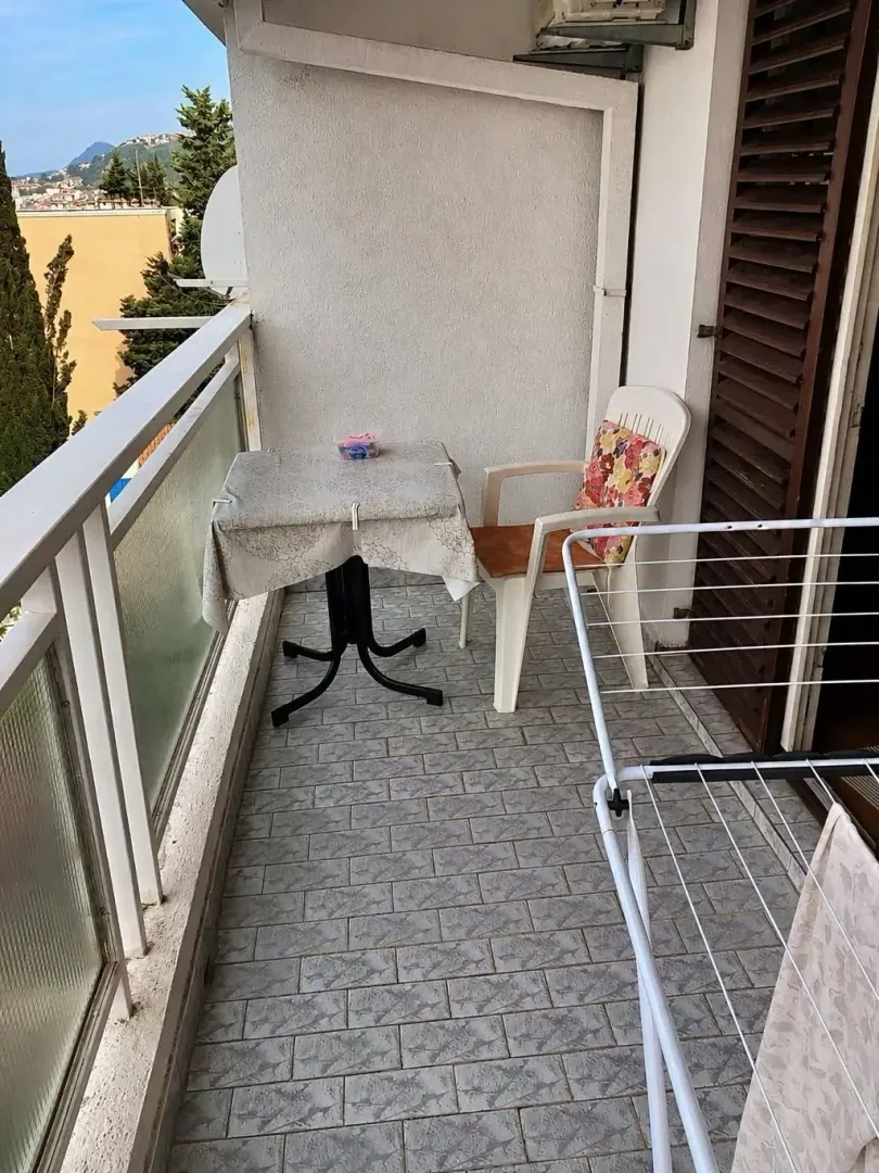 Manji namješteni balkon sa stolom, stolicom i sušilicom za veš.