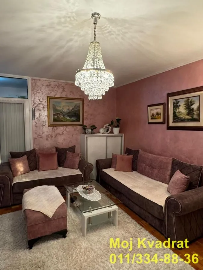 Dnevna soba sa garniturom, stočićem i kristalnim lusterom.
