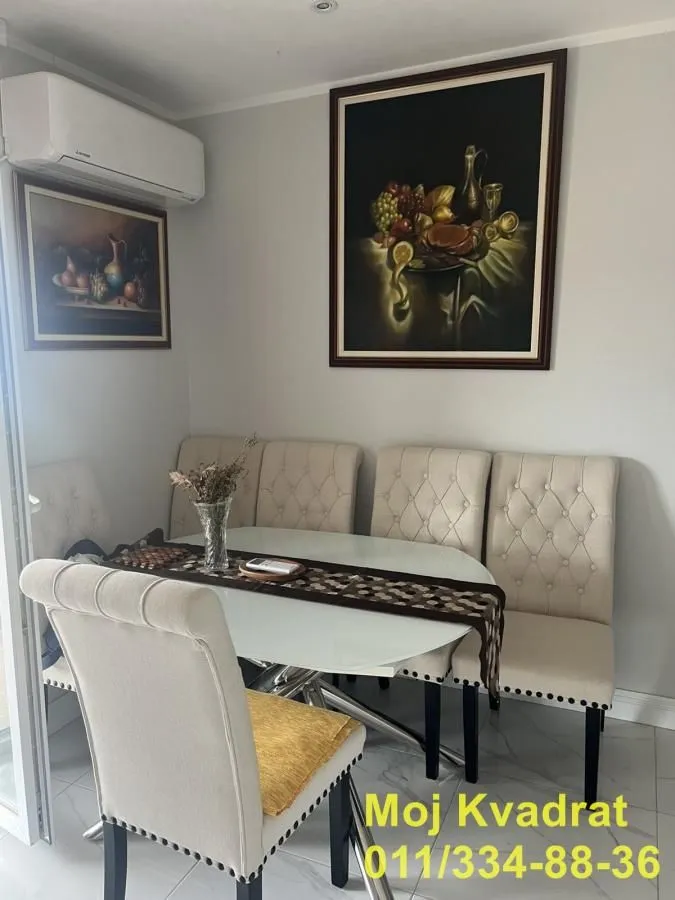 Trpezarija sa stolom, stolicama i slikama na zidu.