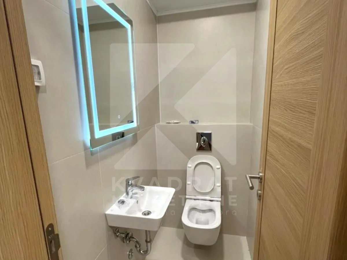 Manje kupatilo sa WC šoljom, umivaonikom i ogledalom sa osvjetljenjem.