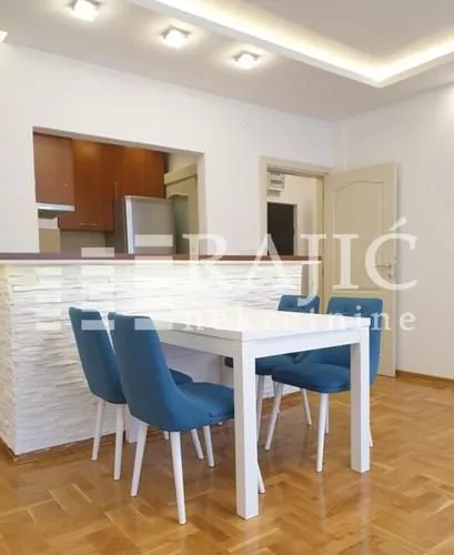 Dining area with a white table and blue chairs connected to the kitchen.