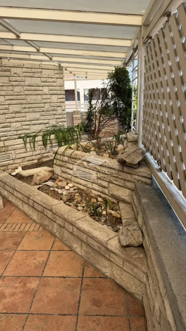 Natkrivena terasa sa kamenim žardinjerama i popločanim podom.