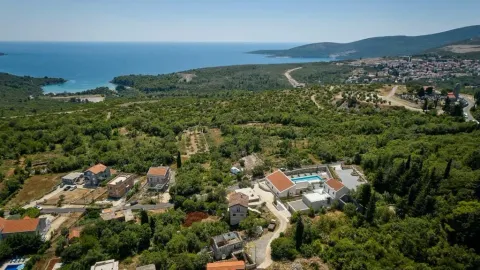 Pogled iz vazduha na imanje sa kućama i bazenom okruženo zelenilom i pogledom na more. - image 9