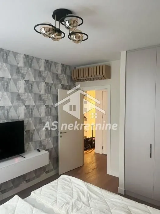 Furnished bedroom with a bed, wardrobe, and television.