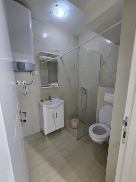 Small bathroom with a shower cabin, washbasin, and toilet. - image 4