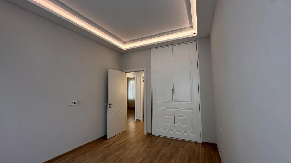 Bedroom with a built-in wardrobe and a drop ceiling with lighting.