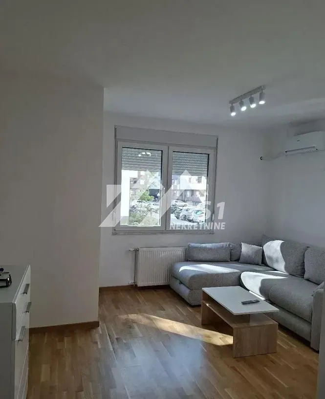 Dnevna soba sa ugaonom garniturom, stočićem i prozorom koji gleda na spoljašnjost.