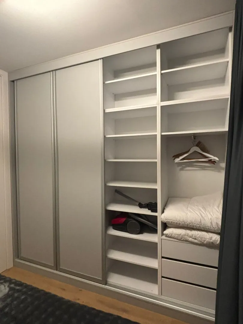 Large built-in wardrobe with shelves and sliding doors in the bedroom.