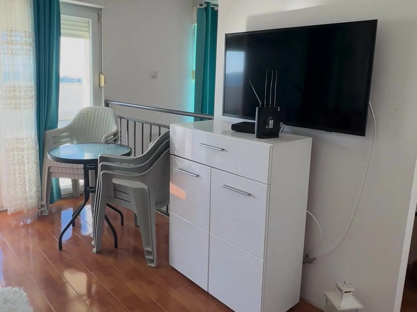 Living room with a white chest of drawers, TV, and terrace access.