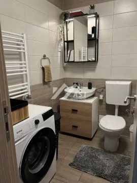 Kupatilo opremljeno umivaonikom, WC šoljom, mašinom za veš i zidnim ormarićem sa ogledalom. - image 8