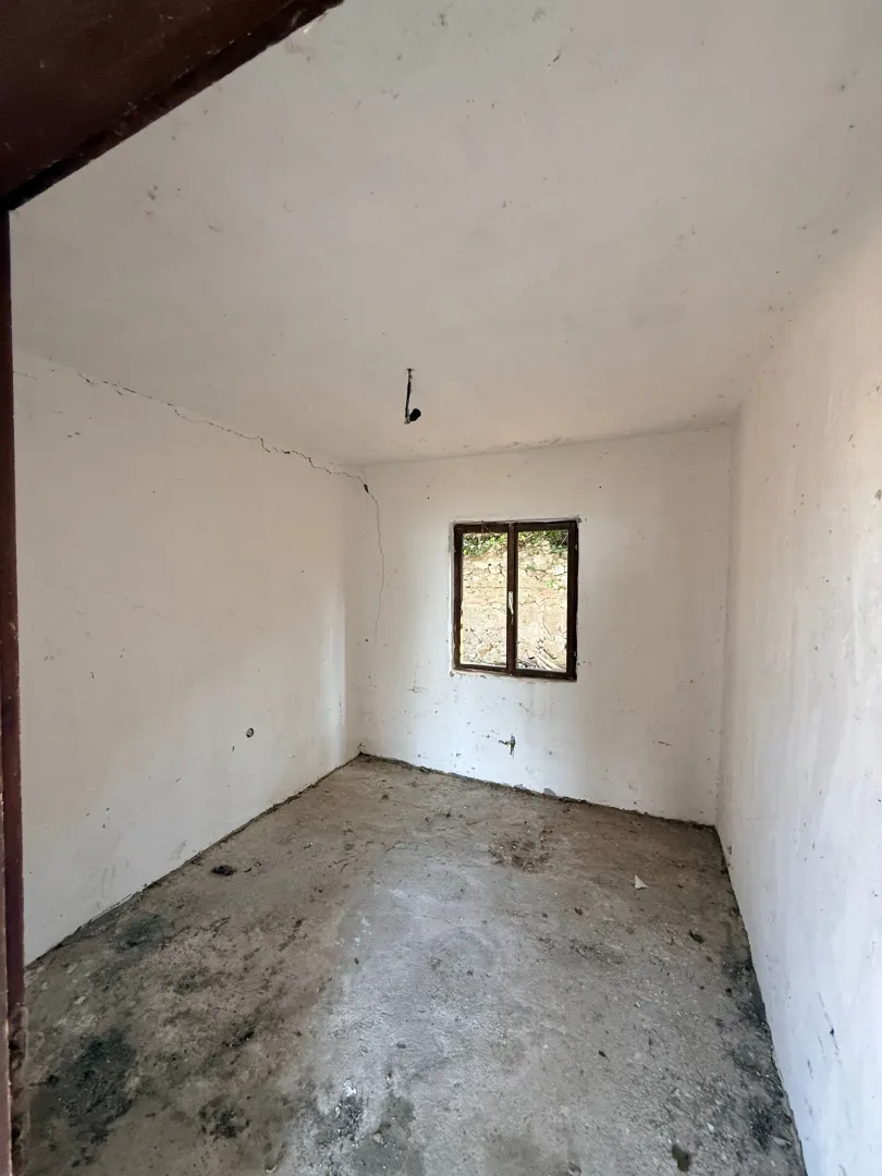 Empty unfurnished room with white walls and a single window.