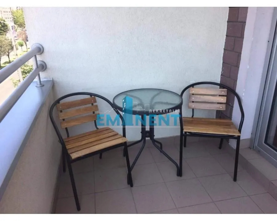 Small furnished balcony with a glass table and two chairs.