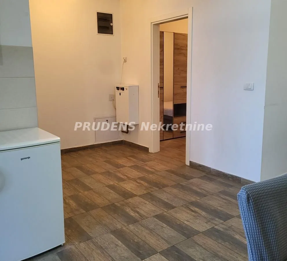Small kitchen with white units and wood-patterned tiled flooring.