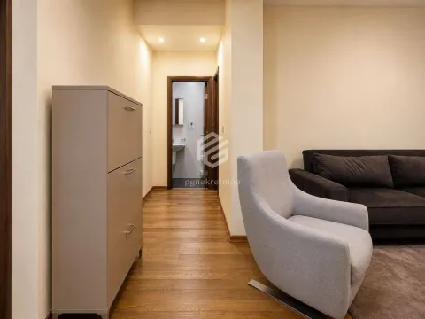 View of a section of the living room with an armchair, sofa, and a passageway leading to the hallway and bathroom. - image 10