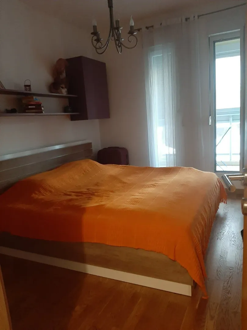 A bedroom featuring a large bed with an orange cover.