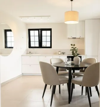 Modern kitchen with a dining area and white cabinetry. - image 20