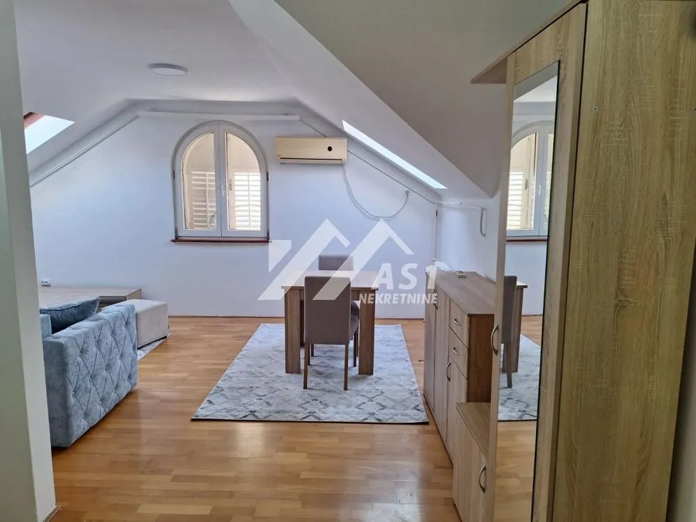 Attic space with a living room, dining area, and hardwood flooring.