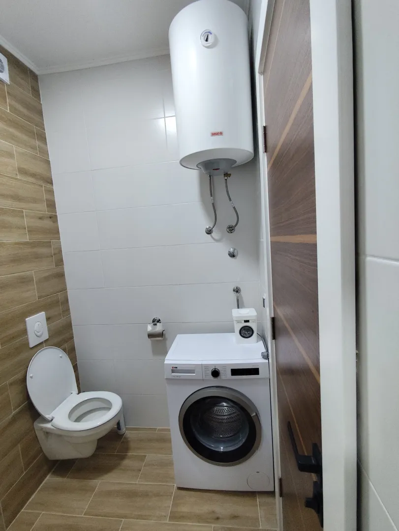 Moderne kupatilo sa WC šoljom, veš mašinom i bojlerom.