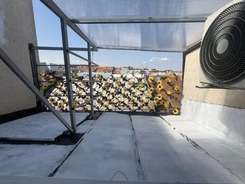 Covered terrace with a decorative fence and a view of roofs. - image 18
