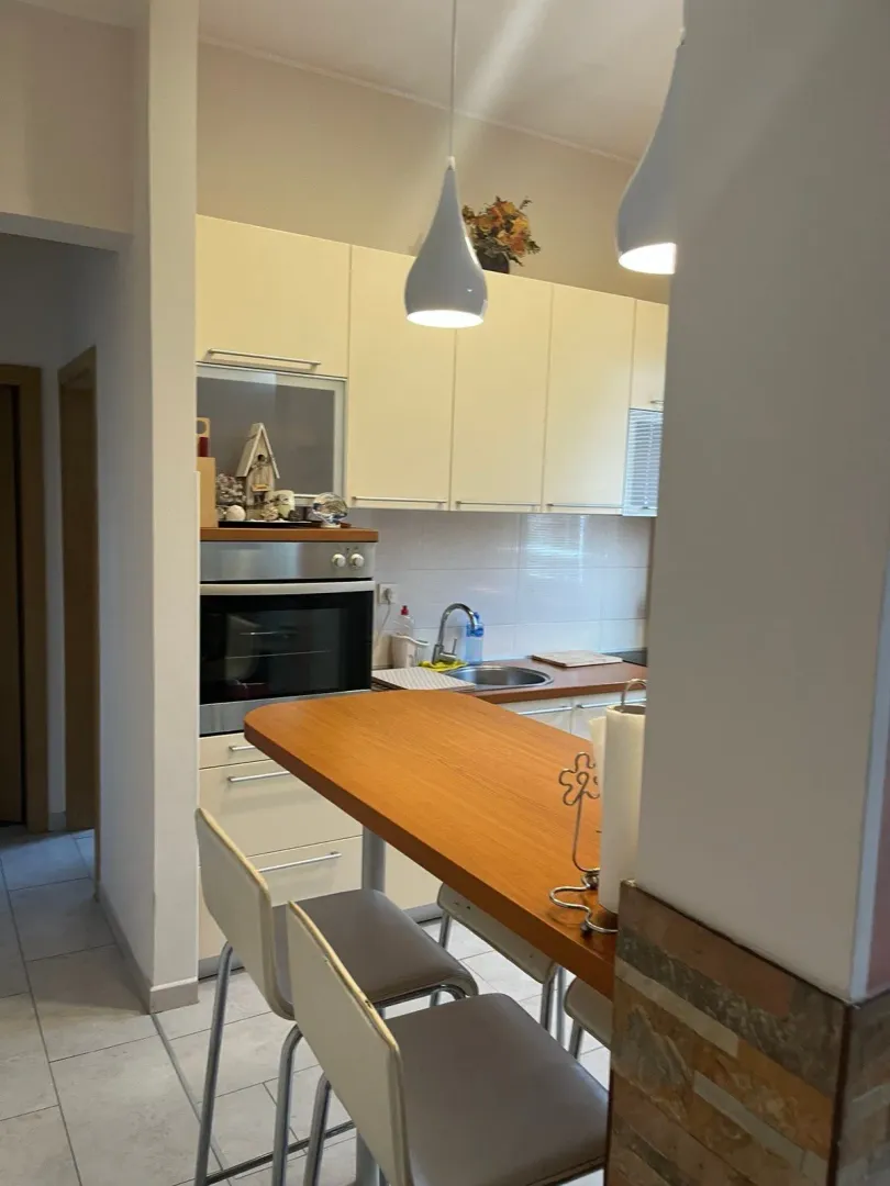 Kitchen with light-colored cabinetry and a wooden breakfast bar.