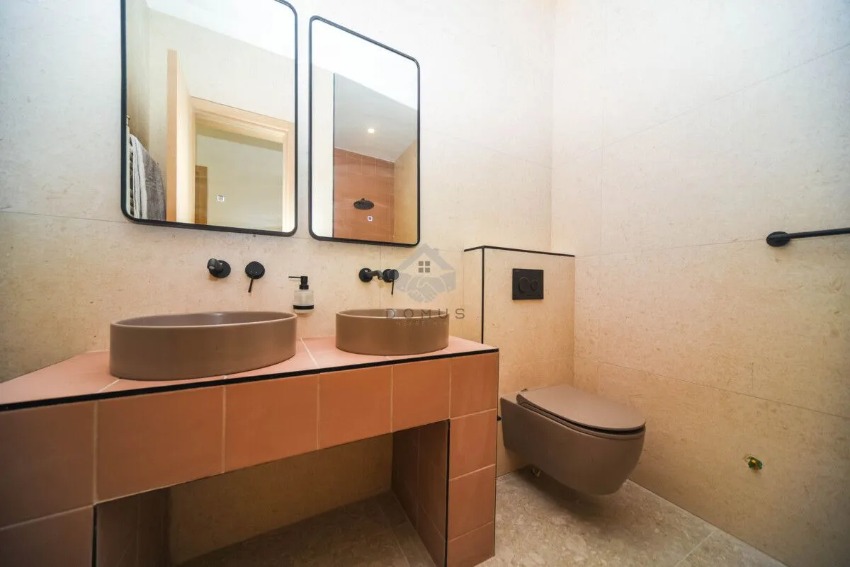 Modern bathroom with two washbasins, mirrors, and a wall-mounted toilet.