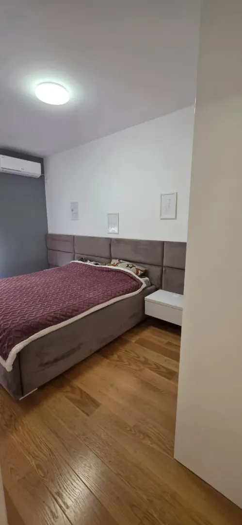 Spavaća soba sa bračnim krevetom i drvenim podom.