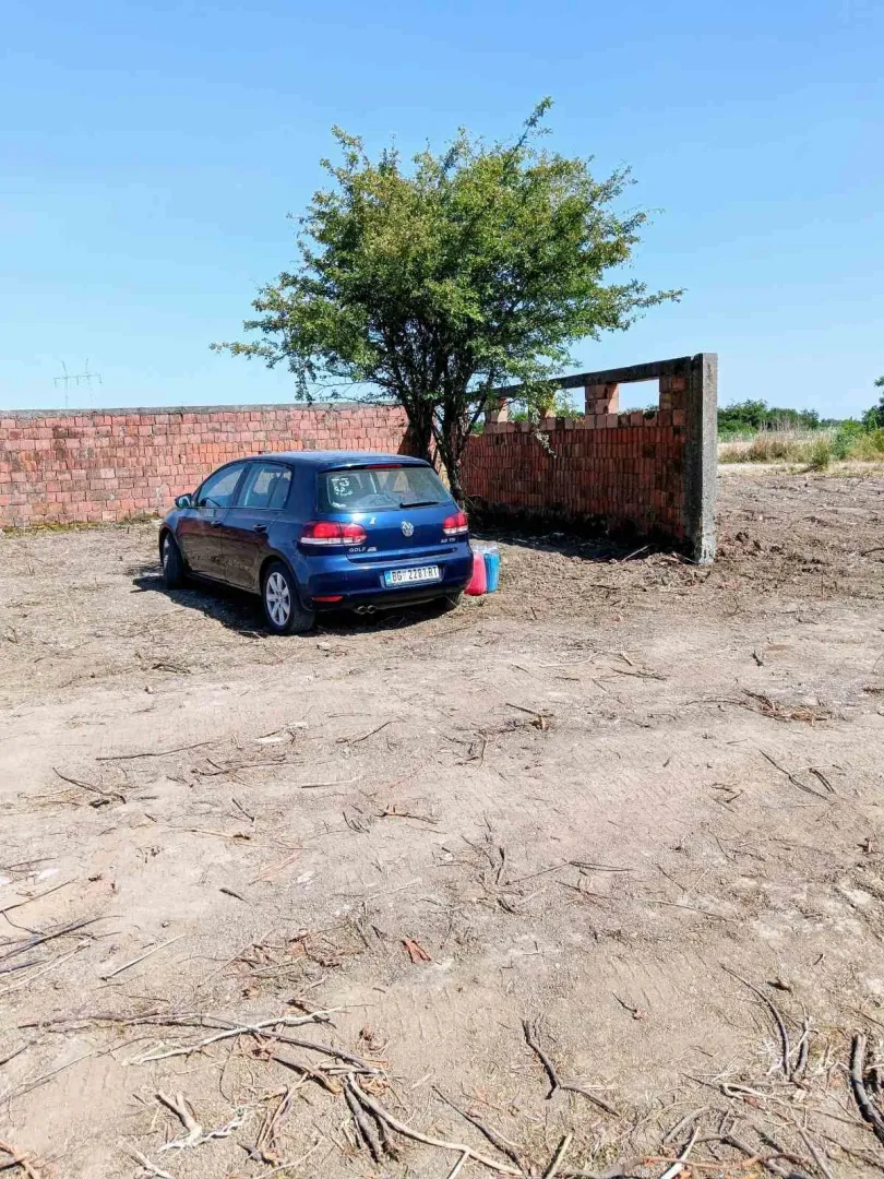 Plac sa ograđenim delom i parkiranim automobilom.