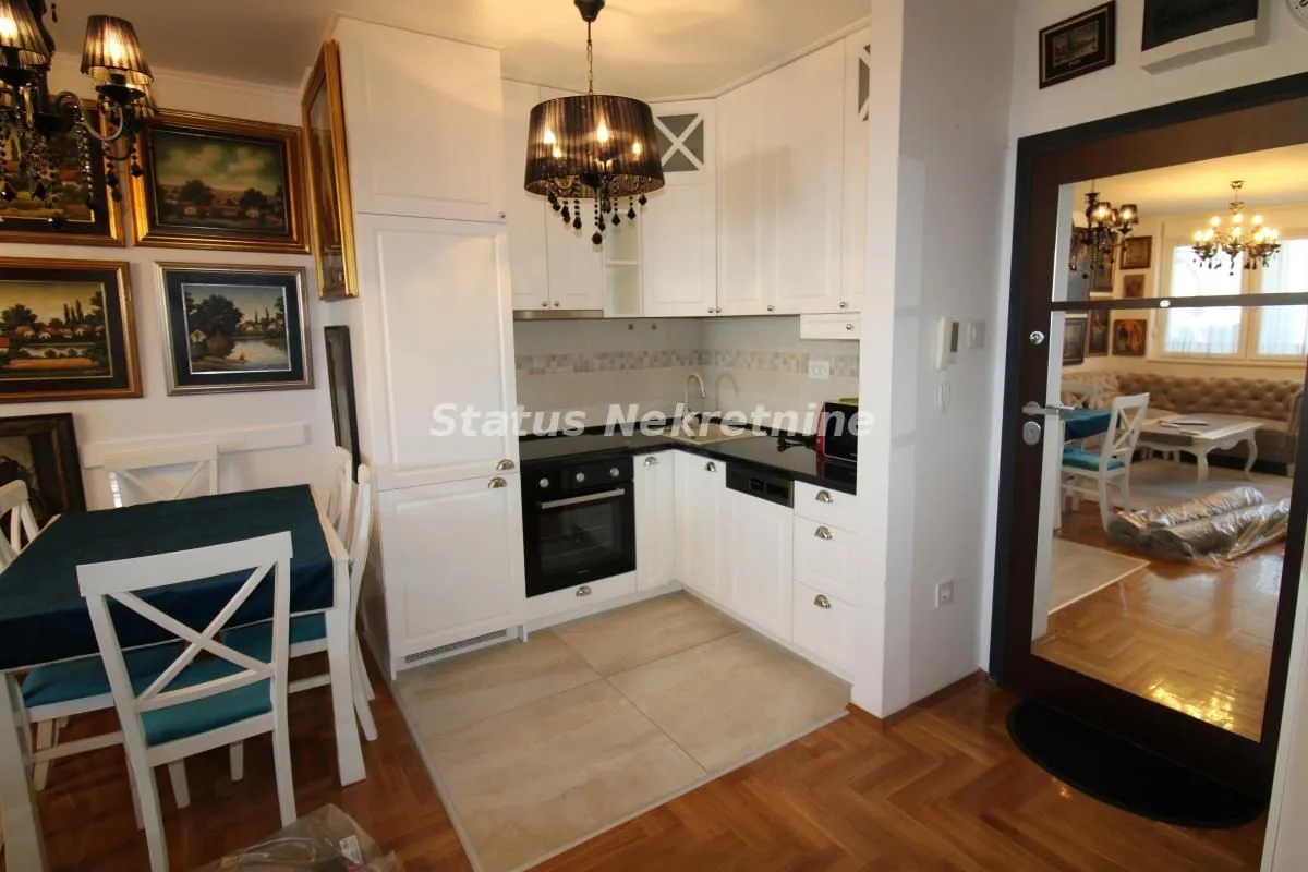 Small white kitchen with a built-in oven and a dining table.