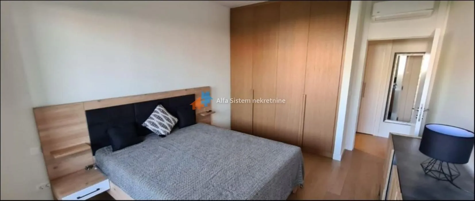 Bedroom with a double bed, fitted wardrobe and wooden flooring.