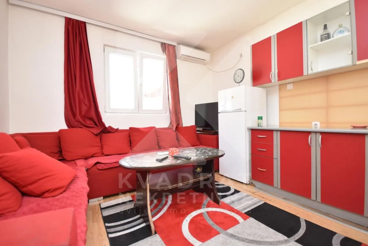 Living room with a red sectional sofa and kitchen cabinets.