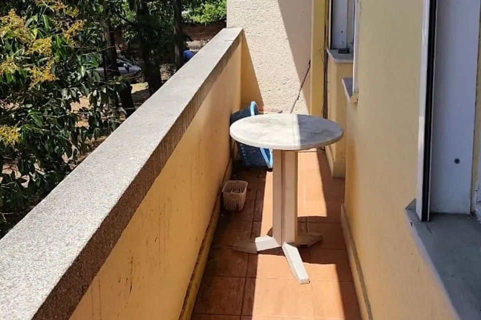Uska terasa sa stolom i pogledom na zelenilo.