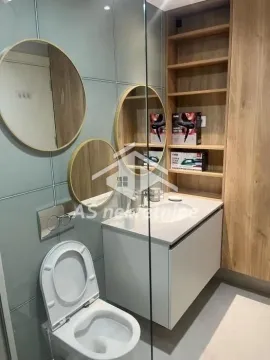 Modern bathroom with a sink, toilet, built-in cabinets, and round mirrors. - image 4