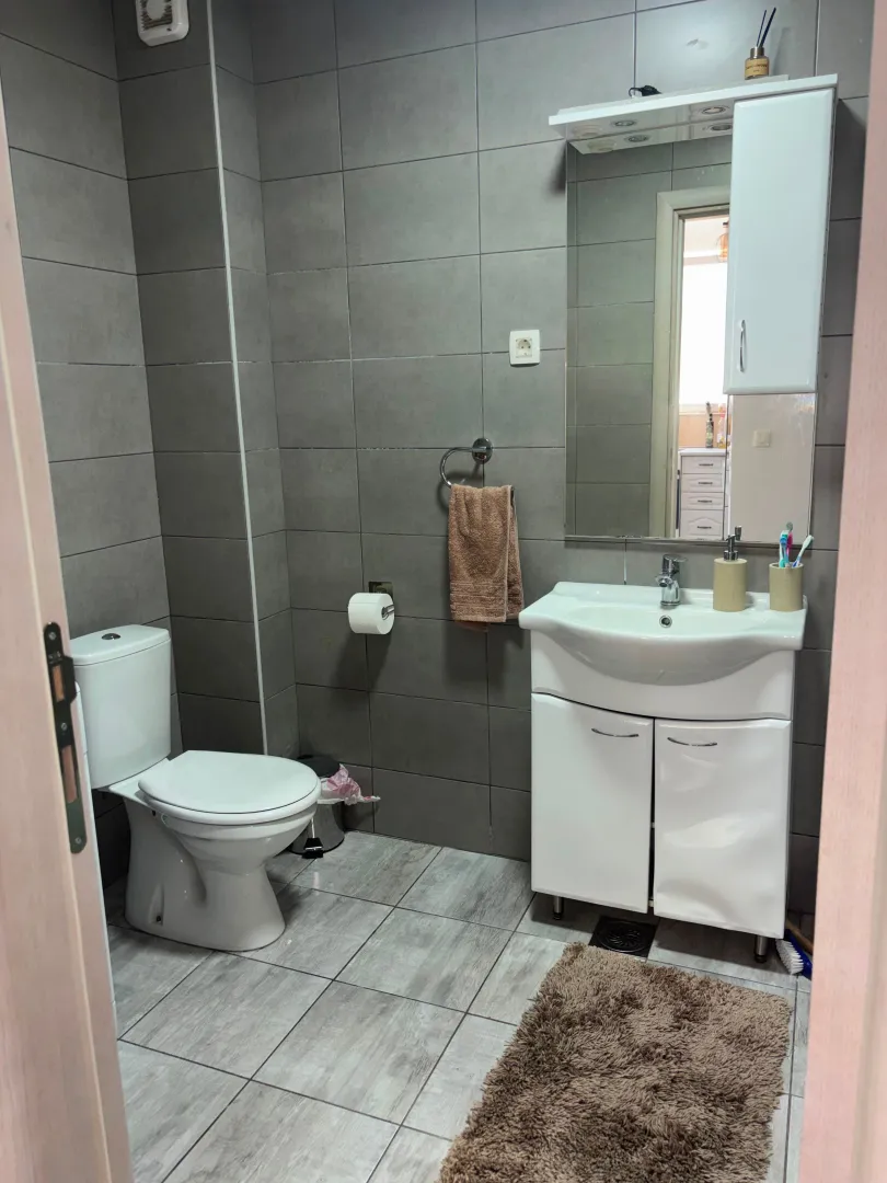 Moderno opremljeno kupatilo sa sivu keramiku i bijelim sanitarijama.