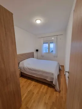 Uređena spavaća soba sa bračnim krevetom, drvenim podom i prozorom. - image 5